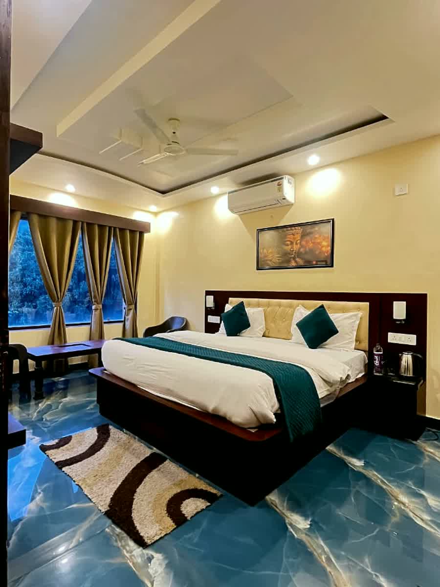A guest room with blue curtains and a framed picture above the bed.