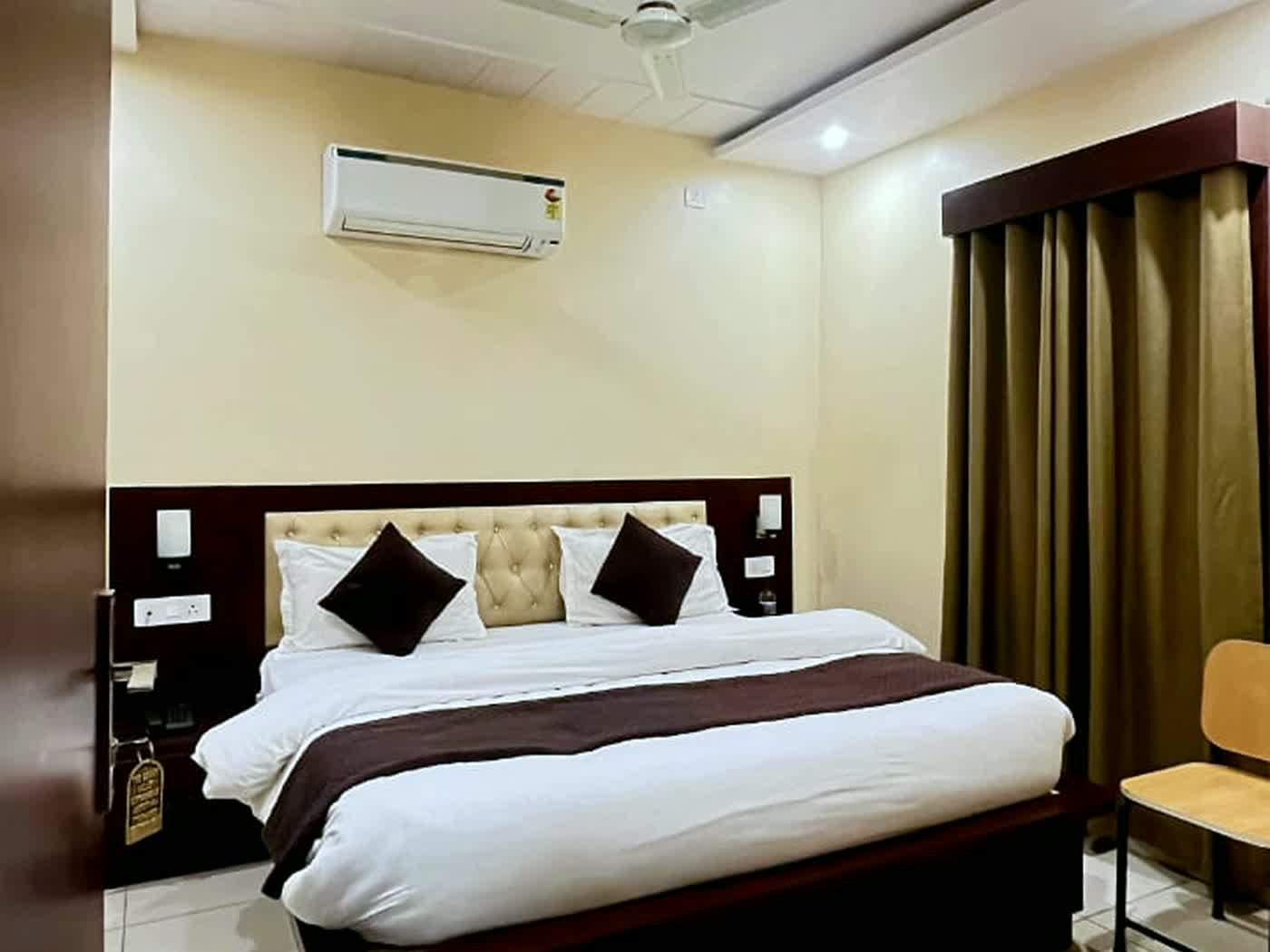 A guest room with a double bed, patterned tile floor, a wardrobe and a wall-mounted air conditioner.
